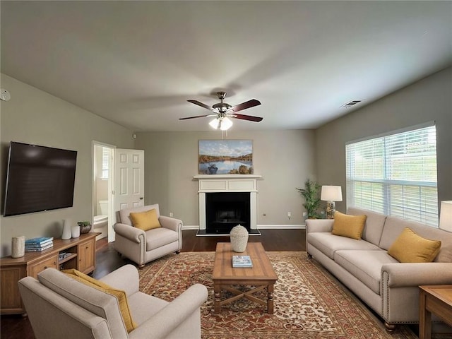 living room featuring ceiling fan and dark wood-type flooring