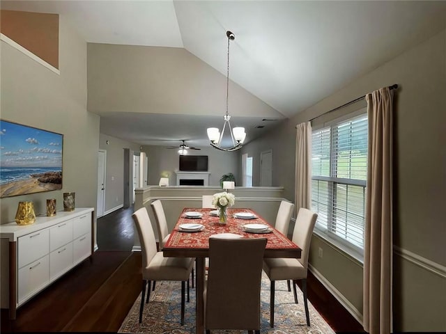 dining room featuring ceiling fan with notable chandelier, vaulted ceiling, a wealth of natural light, and dark hardwood / wood-style floors