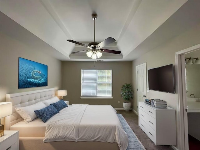 carpeted bedroom with a raised ceiling and ceiling fan