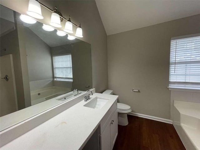 bathroom with vaulted ceiling, wood-type flooring, vanity, a healthy amount of sunlight, and a bathtub