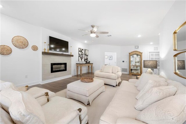 living room featuring hardwood / wood-style floors, ceiling fan, and a fireplace