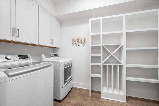 laundry area featuring cabinets, wood-type flooring, and washer and dryer