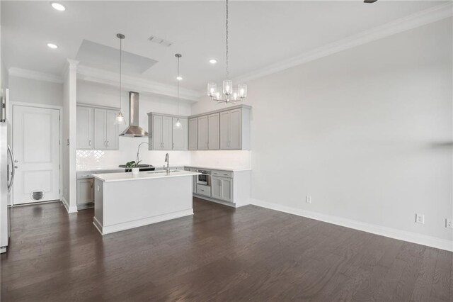 kitchen featuring an island with sink, wall chimney range hood, stainless steel appliances, and pendant lighting