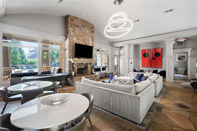 671 Stickley Oak Way, Woodstock, GA 30189 - living room featuring stone tile flooring, decorative columns, a stone fireplace, high vaulted ceiling, and a chandelier