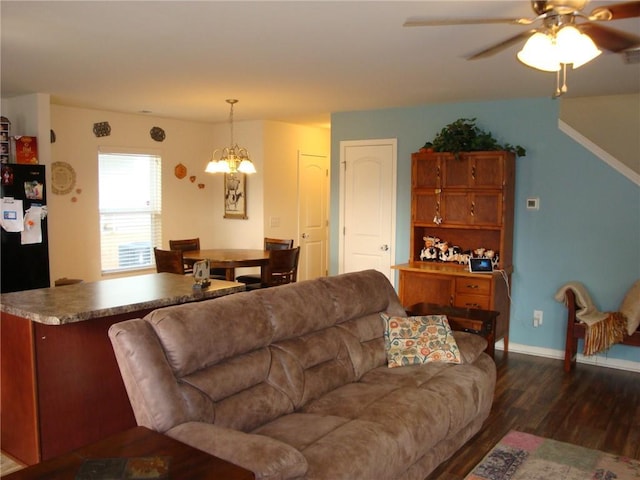 living room featuring ceiling fan with notable chandelier and dark wood-type flooring