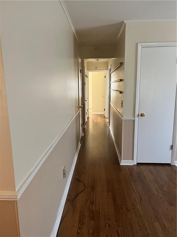 hall featuring dark wood-style floors, baseboards, and crown molding