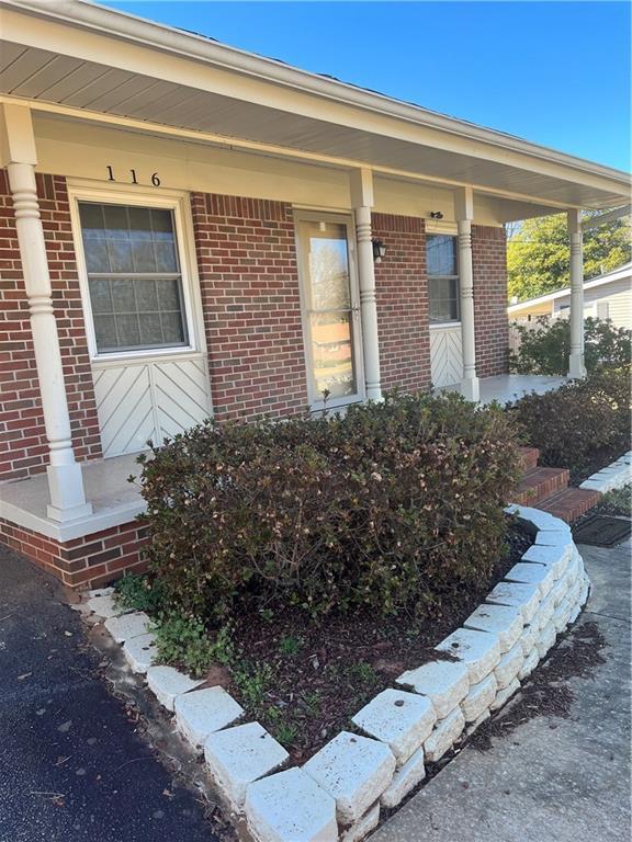 property entrance featuring brick siding and a porch