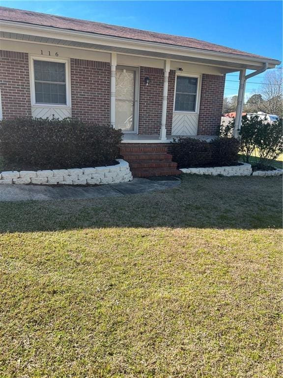 view of front of house with brick siding, a porch, and a front yard