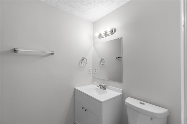bathroom with toilet, a textured ceiling, and vanity
