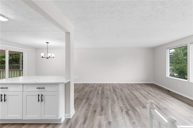 unfurnished living room with a textured ceiling, light wood-style flooring, and plenty of natural light