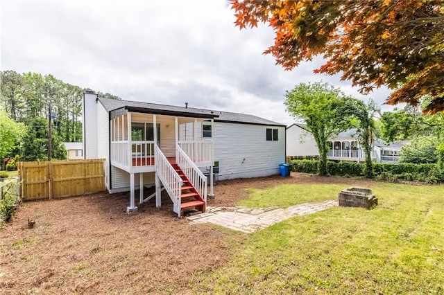 rear view of property featuring a chimney, an outdoor fire pit, fence, stairway, and a yard