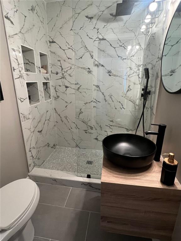 bathroom with vanity, tile patterned floors, toilet, and tiled shower