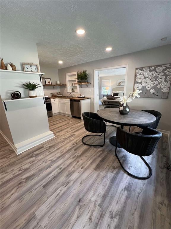 dining area with a textured ceiling, light wood-type flooring, and sink