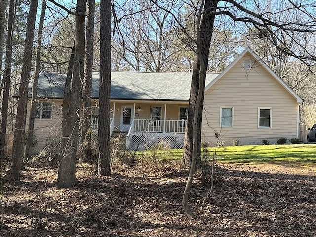 view of front of house featuring a front yard, covered porch, and roof with shingles