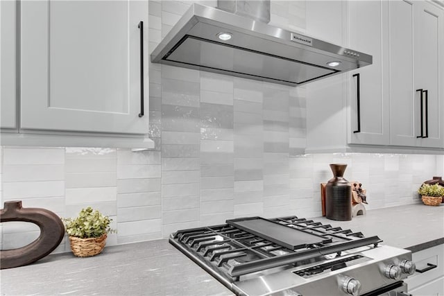 kitchen featuring decorative backsplash, white cabinets, exhaust hood, and stainless steel range with gas stovetop