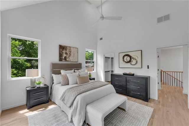 bedroom featuring ceiling fan, light wood-type flooring, high vaulted ceiling, and multiple windows