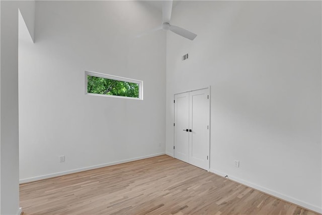 unfurnished room with ceiling fan, light hardwood / wood-style floors, and a high ceiling