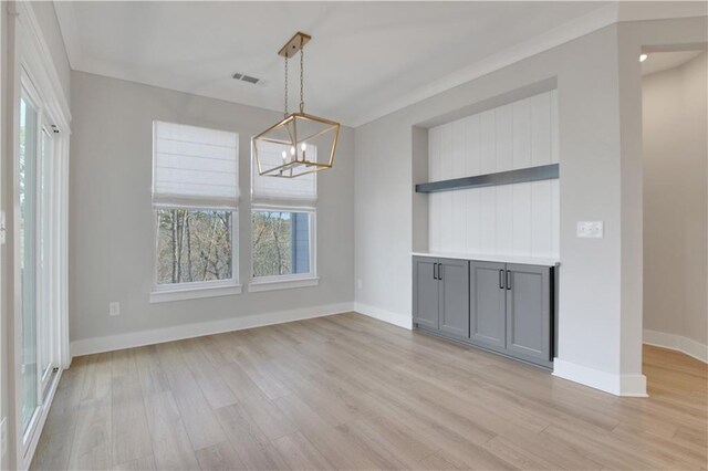 unfurnished dining area with baseboards, a chandelier, light wood-style floors, and visible vents