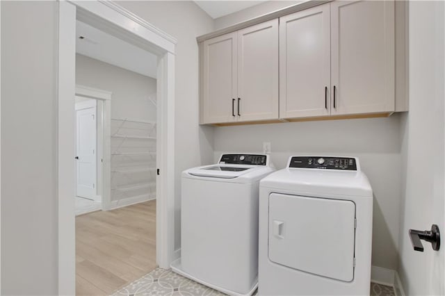 laundry area featuring light wood-type flooring, baseboards, independent washer and dryer, and cabinet space