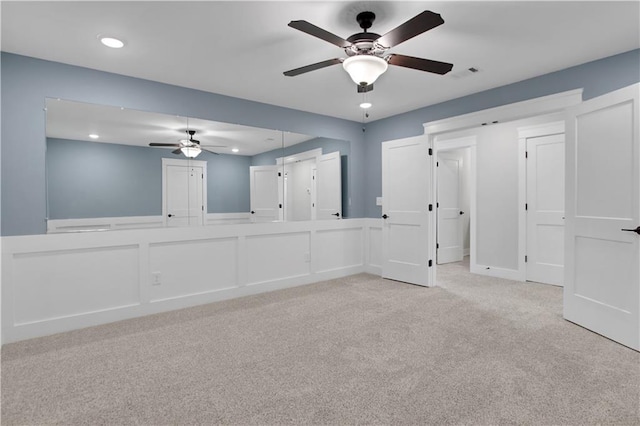 carpeted spare room with wainscoting, a ceiling fan, visible vents, and recessed lighting