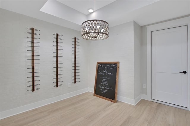 unfurnished dining area with baseboards, a chandelier, and wood finished floors