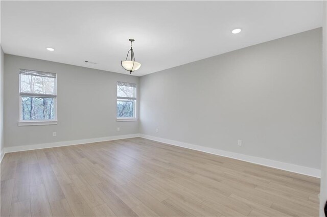 empty room featuring light wood-type flooring, baseboards, and recessed lighting