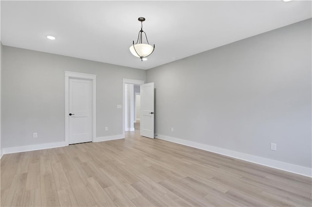 spare room with baseboards, recessed lighting, and light wood-style floors