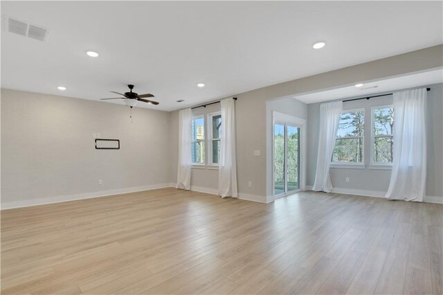 empty room with baseboards, light wood-style flooring, visible vents, and ceiling fan