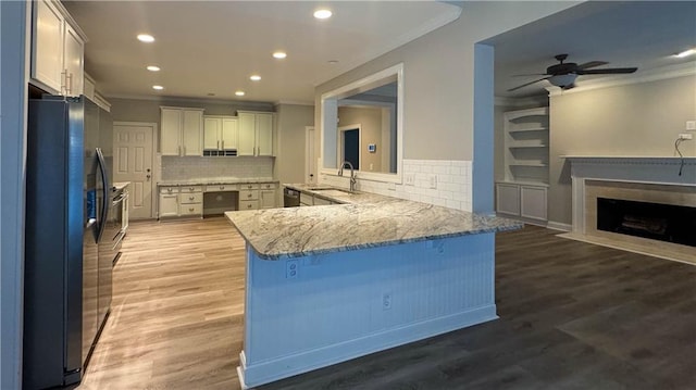 kitchen featuring kitchen peninsula, tasteful backsplash, stainless steel appliances, sink, and wood-type flooring