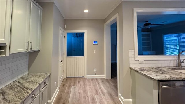 kitchen with stainless steel dishwasher, light stone counters, and backsplash