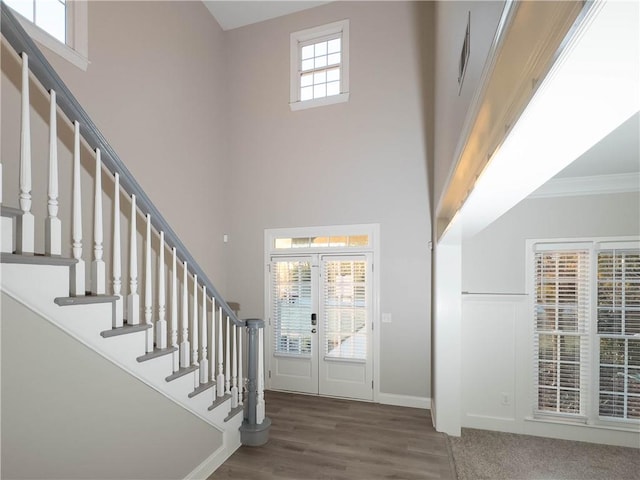 foyer entrance with a towering ceiling, french doors, dark hardwood / wood-style flooring, and ornamental molding