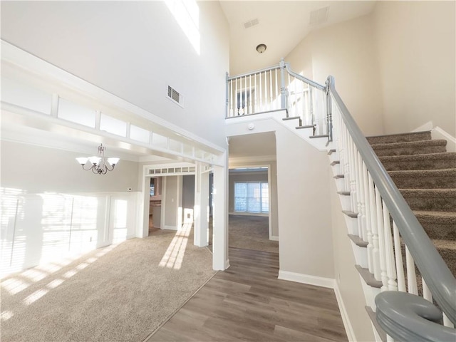 stairway featuring hardwood / wood-style floors, a high ceiling, and a notable chandelier