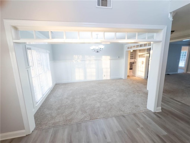 empty room featuring wood-type flooring and an inviting chandelier