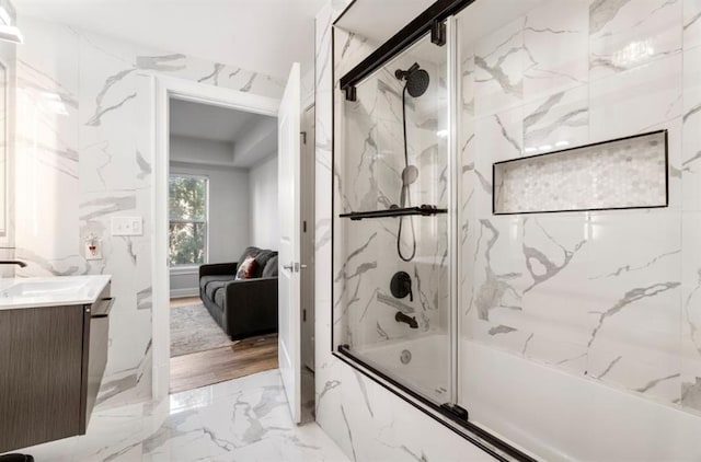 ensuite bathroom with marble finish floor, connected bathroom, bath / shower combo with glass door, stone wall, and vanity