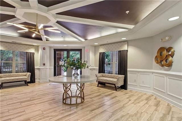 living area with a decorative wall, wainscoting, and a tray ceiling