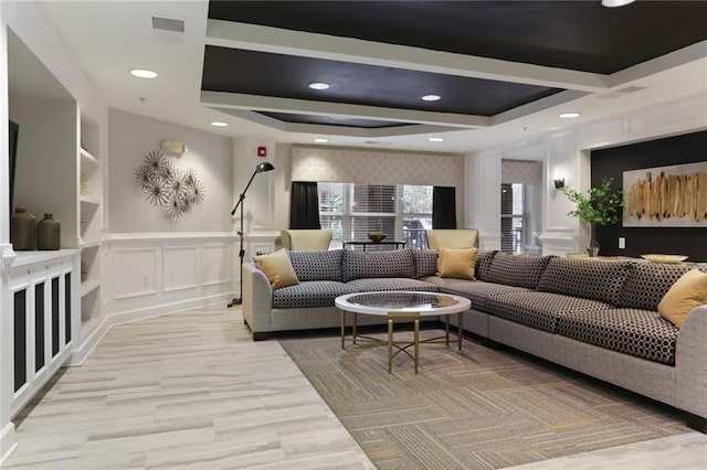 living room featuring visible vents, a wainscoted wall, recessed lighting, a decorative wall, and a raised ceiling