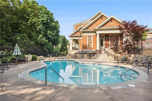 pool with a patio area and fence