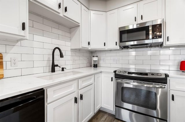 kitchen with decorative backsplash, white cabinets, appliances with stainless steel finishes, and a sink