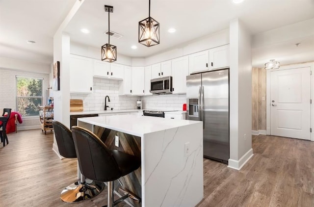 kitchen featuring visible vents, backsplash, appliances with stainless steel finishes, and wood finished floors