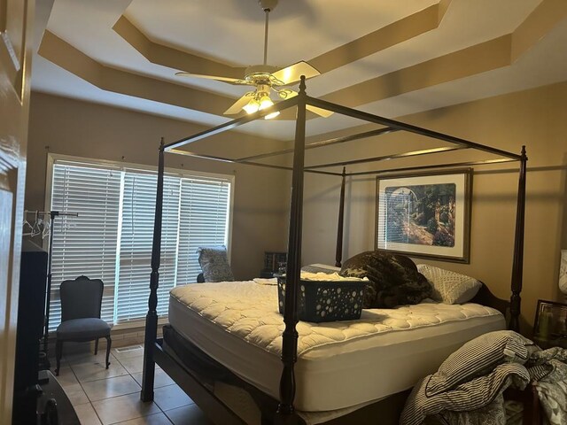 tiled bedroom featuring a raised ceiling and ceiling fan