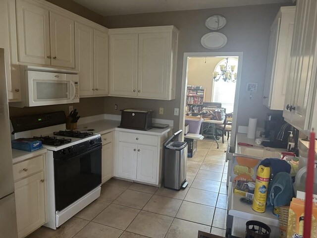 kitchen featuring white cabinetry, light tile patterned floors, white appliances, and an inviting chandelier