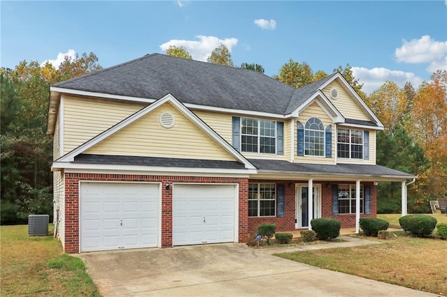 view of front of property featuring central air condition unit, covered porch, a front yard, and a garage