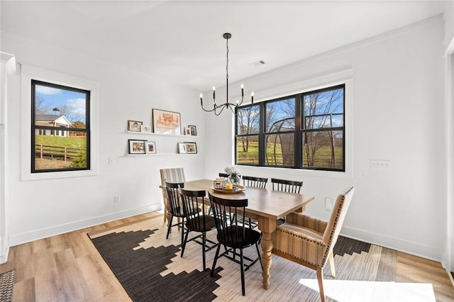 dining room with visible vents, light wood-style flooring, baseboards, and an inviting chandelier