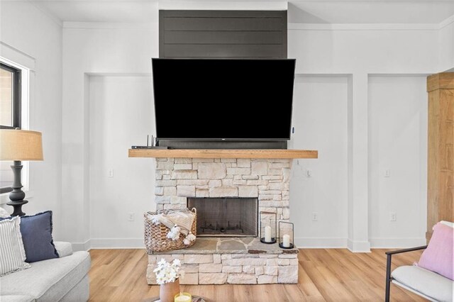 living room with light wood-type flooring, ceiling fan, a fireplace, and baseboards