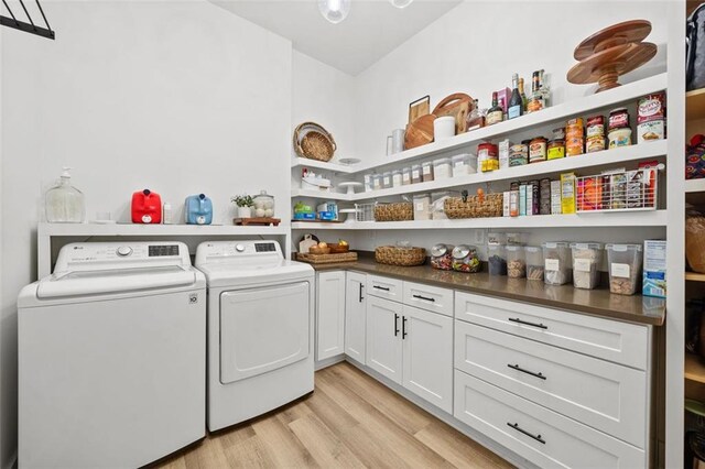 laundry room with cabinet space, light wood-style flooring, and washer and dryer