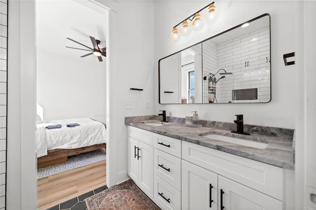 ensuite bathroom featuring ceiling fan, a sink, a tile shower, and double vanity