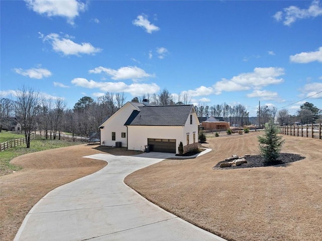 view of side of property with an attached garage, fence, and concrete driveway