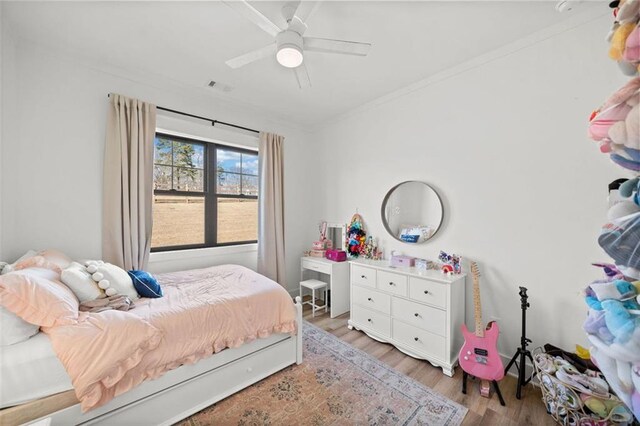 bedroom featuring light wood-style floors, ceiling fan, visible vents, and ornamental molding