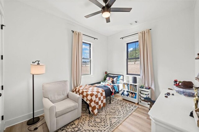 bedroom featuring a ceiling fan, baseboards, visible vents, and light wood finished floors