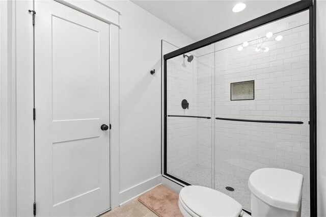 bathroom featuring toilet, a stall shower, and tile patterned flooring